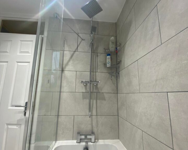 A white tiled bathroom with a glass shower enclosure in Southampton.