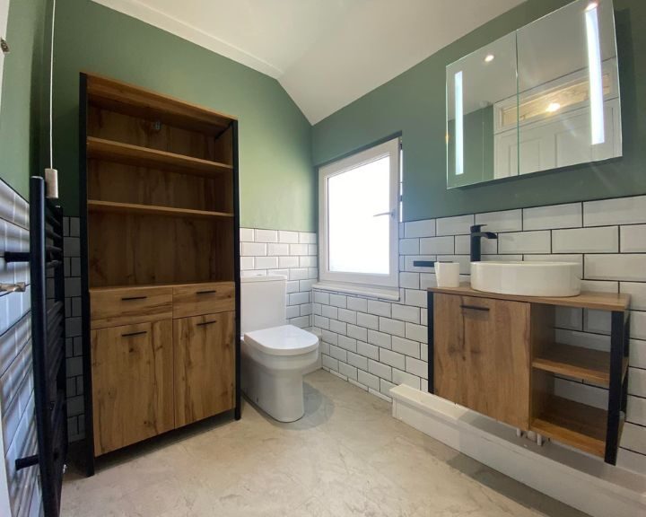 A new bathroom fitted in a house in Southampton featuring white tiled walls, wooden floating cabinet with sink, wooden unit and a new toilet.