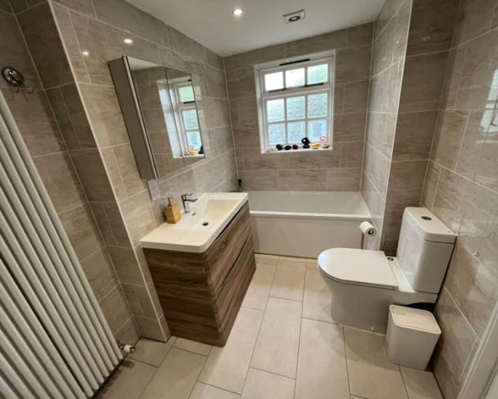 A bathroom that has had new marble-effect wall tiles and cream floor tiles installed as part of a new bathroom fitting.