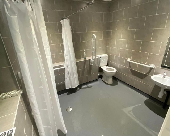 A disabled bathroom in Southampton featuring non-slip flooring, grab bars and rails, an accessible toilet and tiled walls.