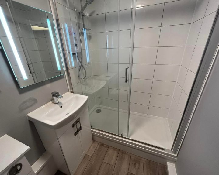 A bathroom installation in Southampton featuring a shower enclosure, white tiled walls, free-standing sink with cabinet, vinyl flooring and a new toilet.