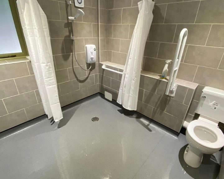 A disabled bathroom in Southampton featuring non-slip flooring, grab bars and rails, an accessible toilet and tiled walls.