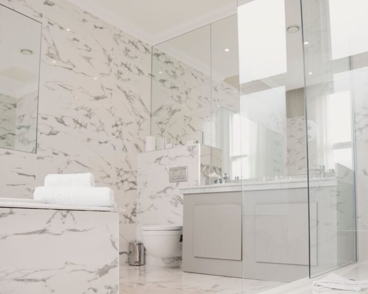 A new bathroom installation in Southampton featuring marble walls, tiled floors, a walk-in shower, bathtub and sink with cabinets.